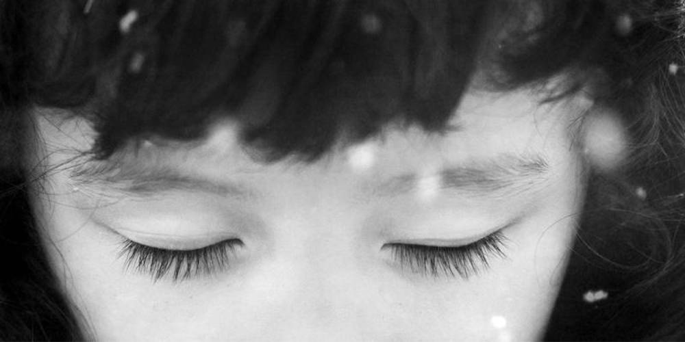 Imagem em preto e branco, com destaque para os olhos fechados de uma criança oriental. Ilustra o tema Deficiência Visual e Cegueira